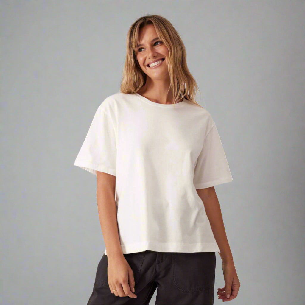 Woman wearing a white t-shirt and black pants against a light gray background