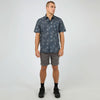 Man wearing a patterned shirt and shorts on a white background