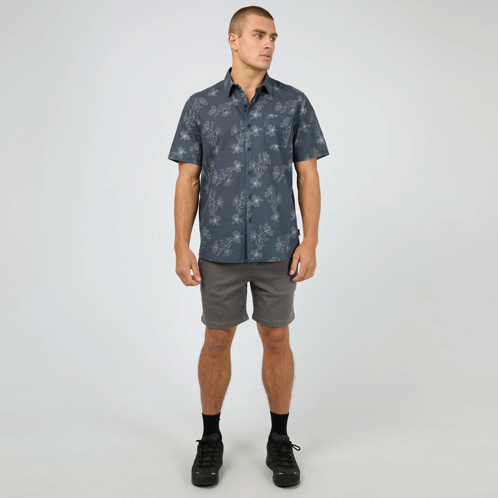 Man wearing a dark blue patterned shirt against a plain background