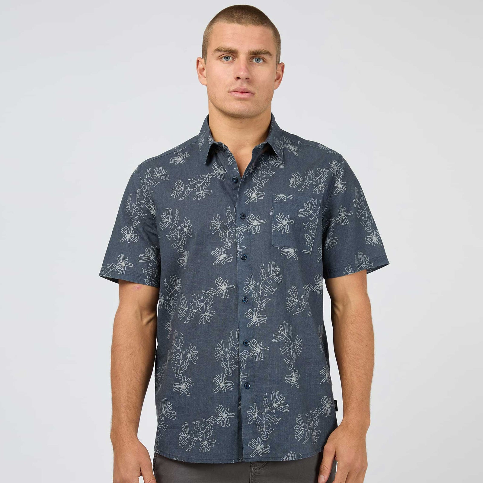 Man wearing a dark blue patterned shirt against a plain background