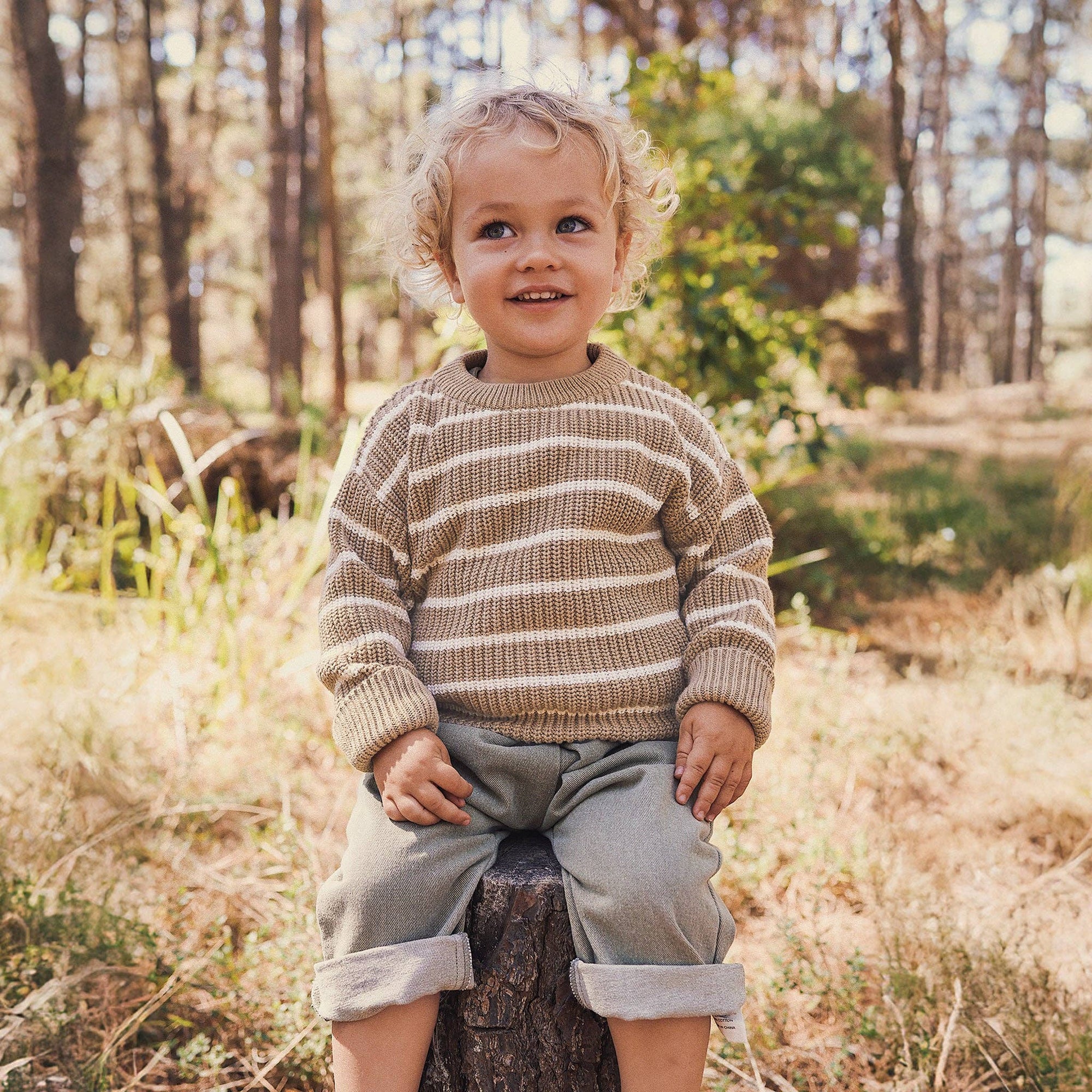 Child sitting on a log in a forest