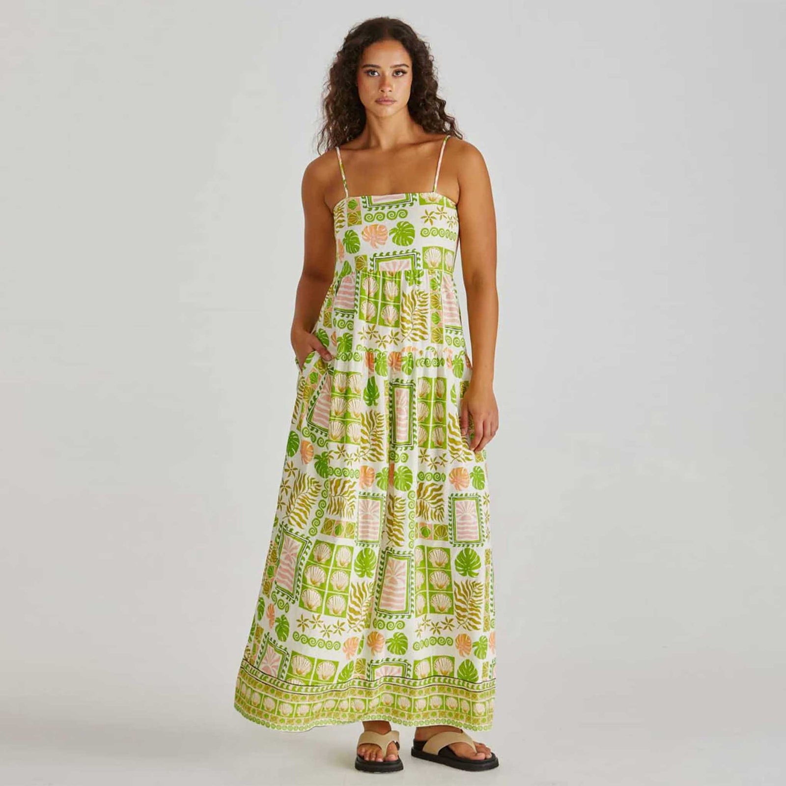 Woman wearing a green and white patterned dress on a plain background