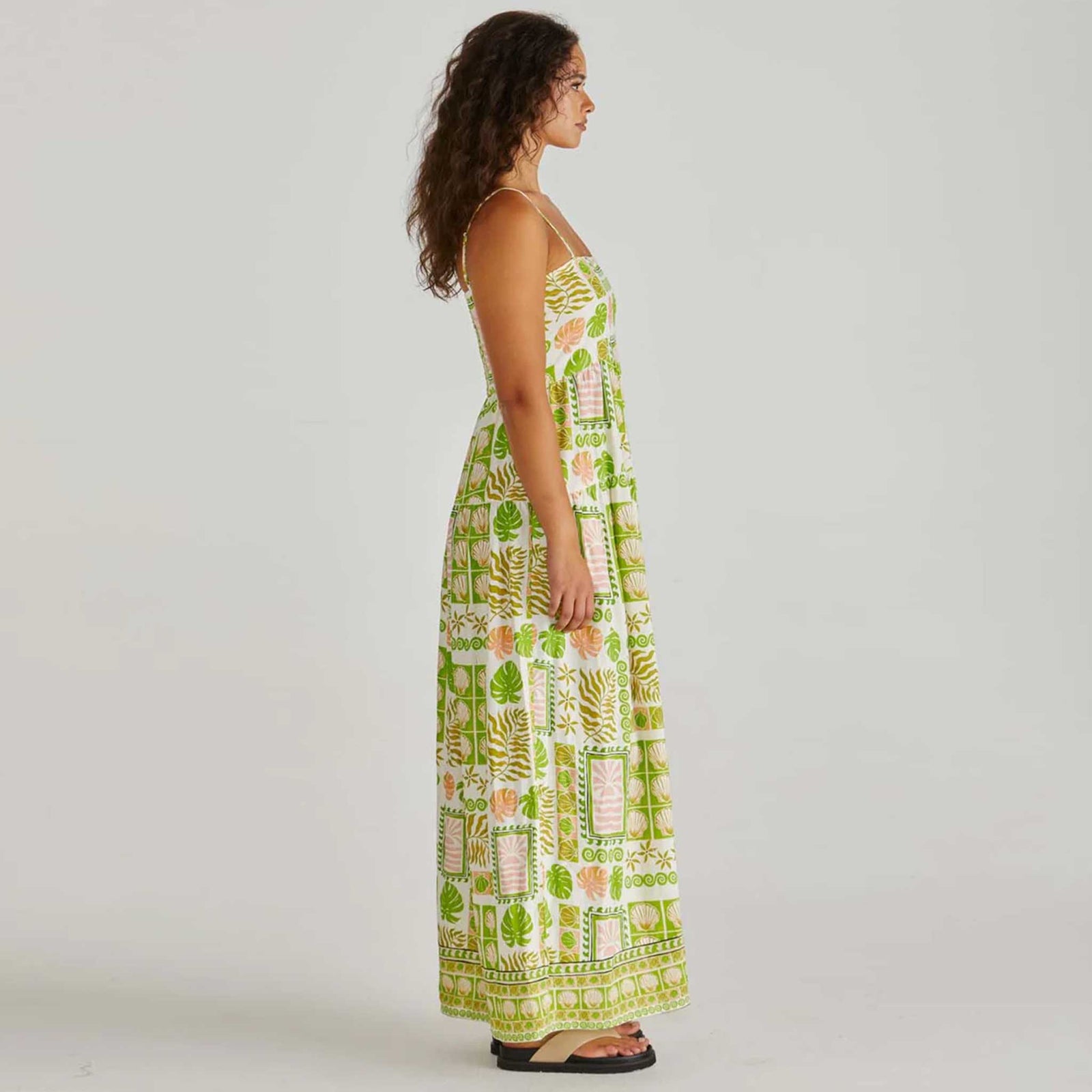 Woman wearing a green and white patterned dress on a plain background