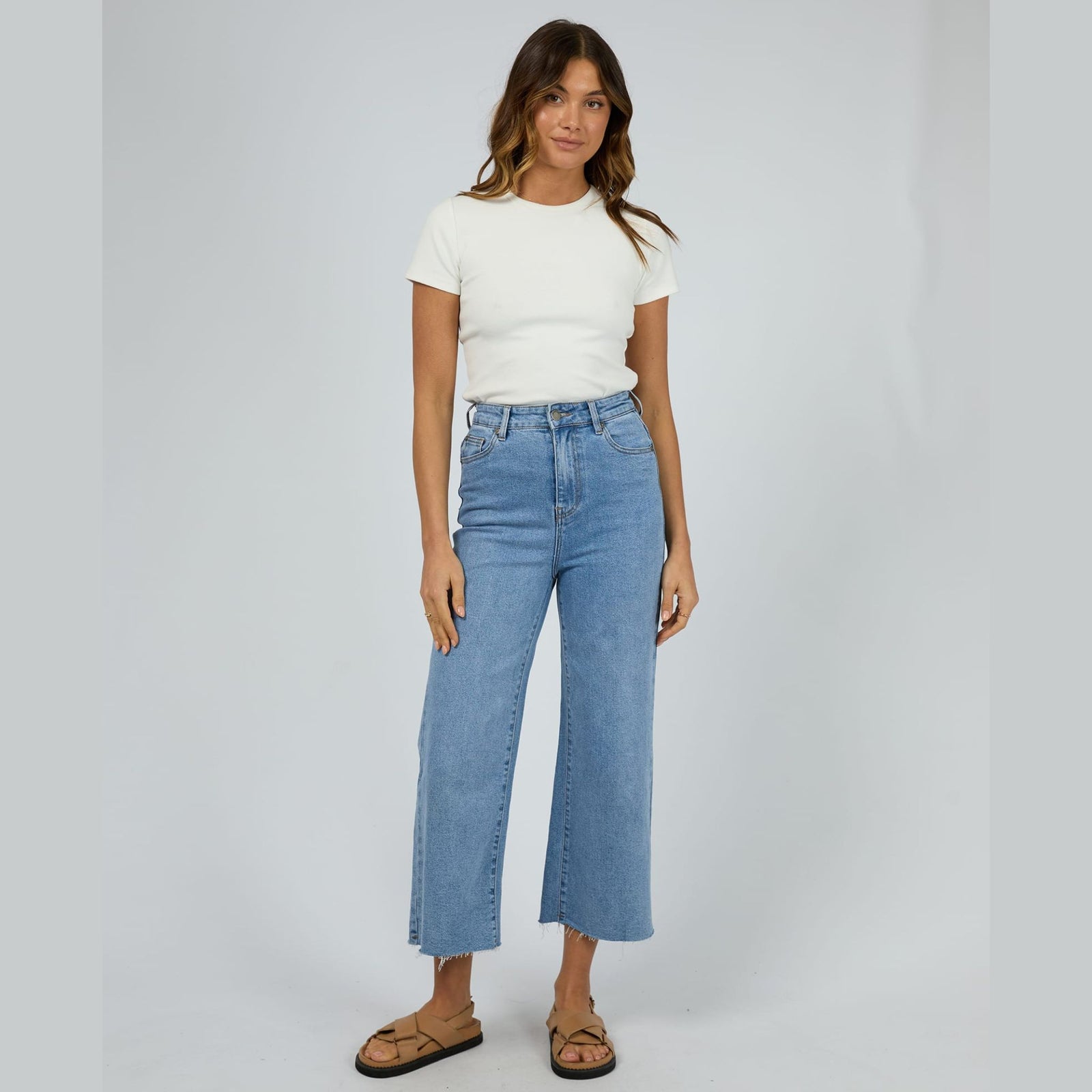 Person wearing light blue wide-leg jeans on a plain background