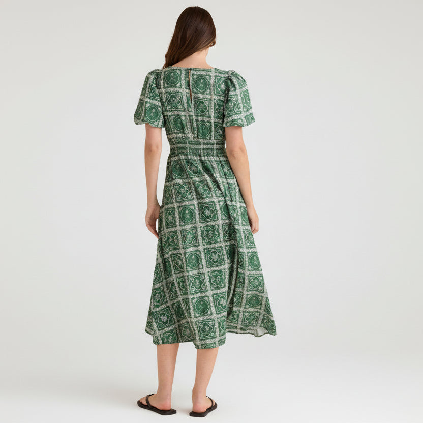 Woman wearing a green patterned dress on a white background