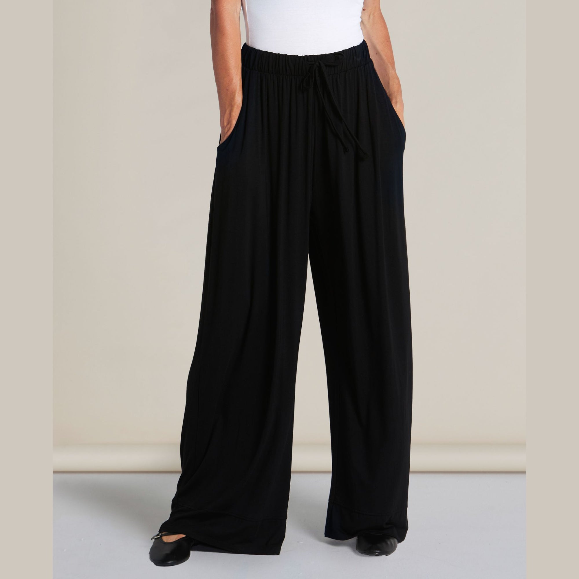 Person wearing black wide-leg pants on a plain background