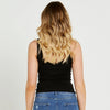 Person wearing a black tank top and blue jeans on a plain background