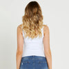 Person wearing a white tank top and blue jeans on a plain background
