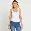 Woman wearing a white tank top and blue jeans on a white background