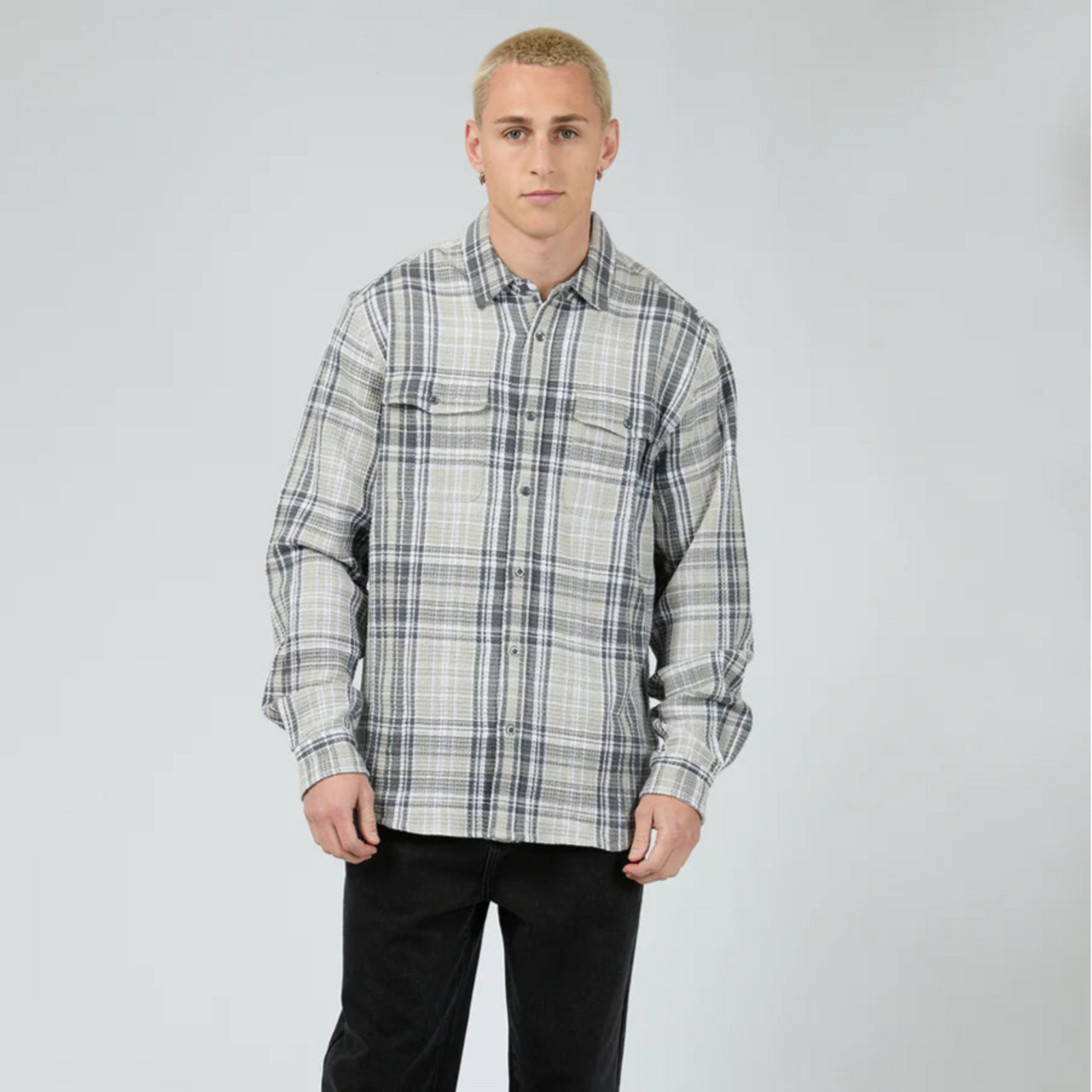 Person wearing a plaid shirt and black pants on a white background
