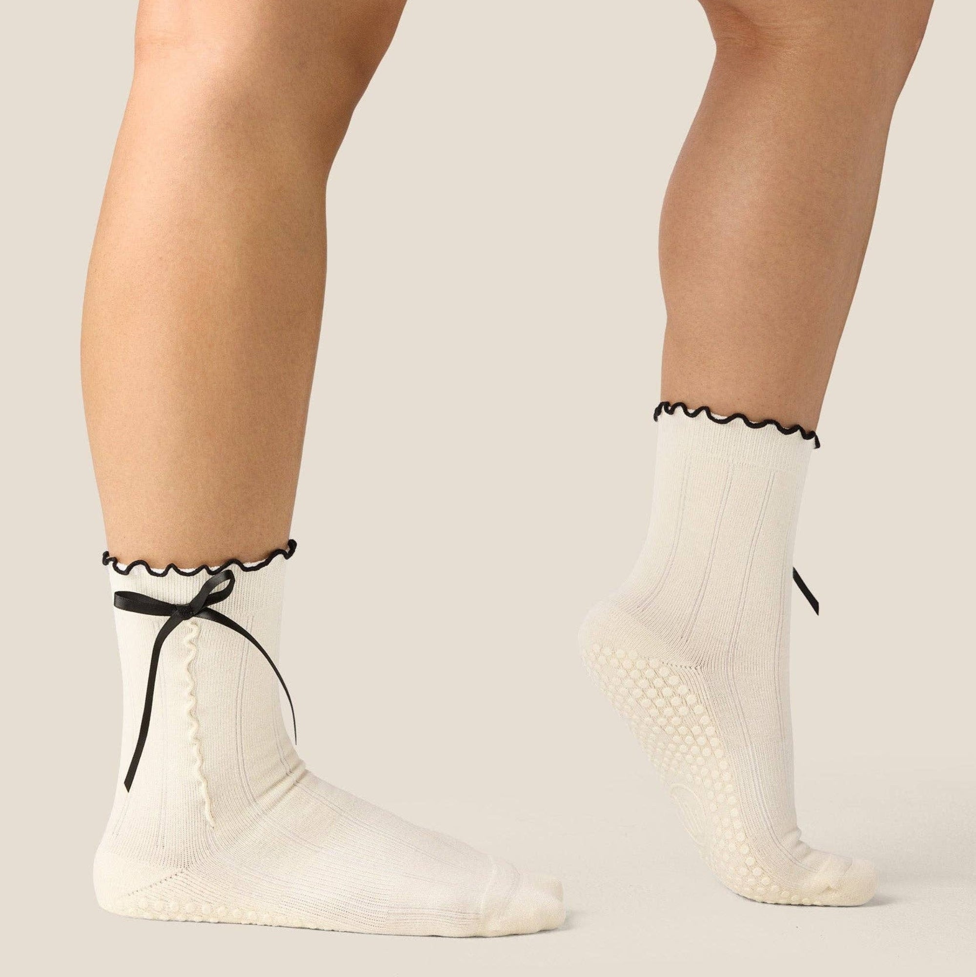 White socks with black trim worn by a person on a plain background