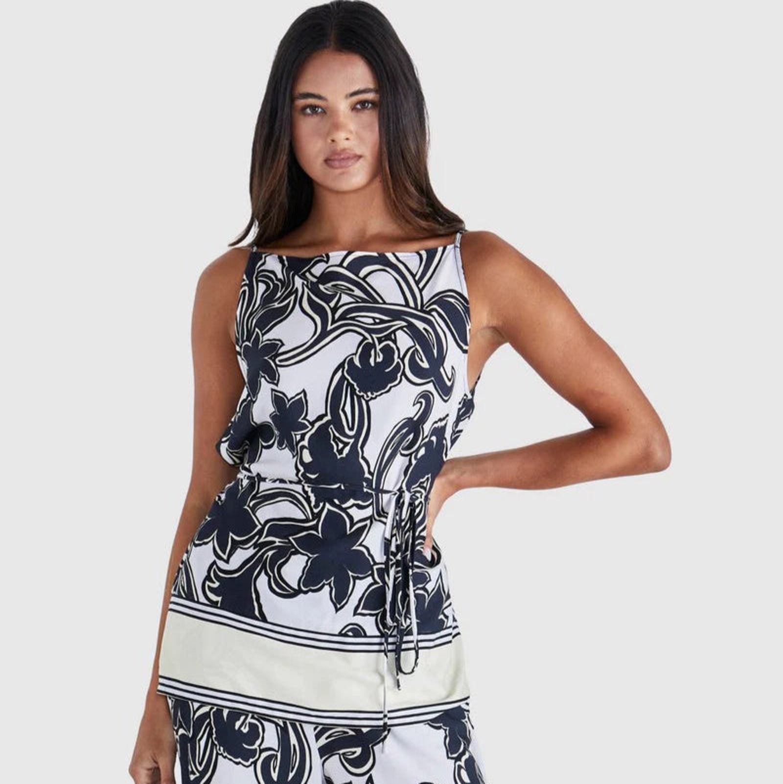 Woman wearing a sleeveless top and pants with a black and white floral pattern on a white background