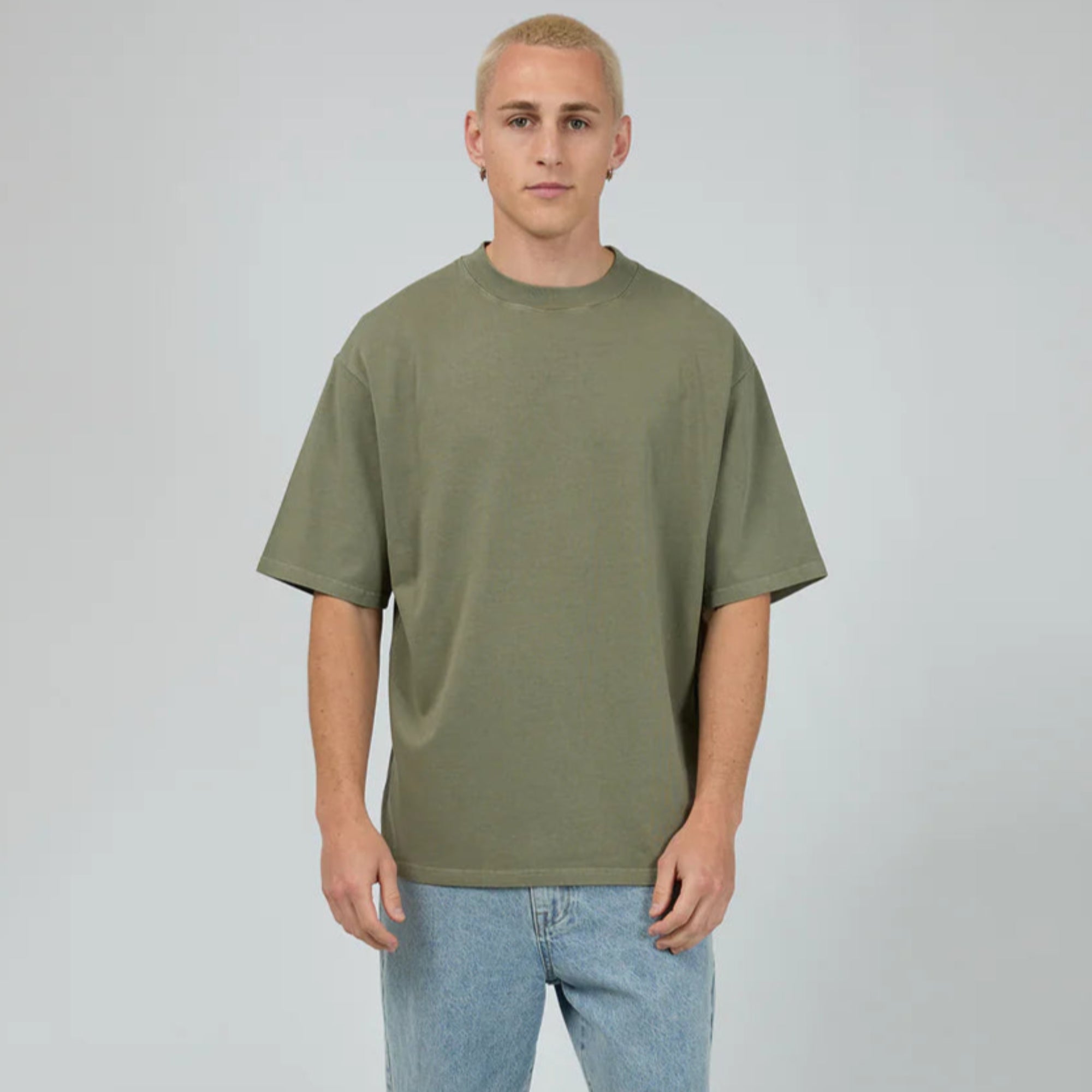 Person wearing an olive green t-shirt and light blue jeans on a white background