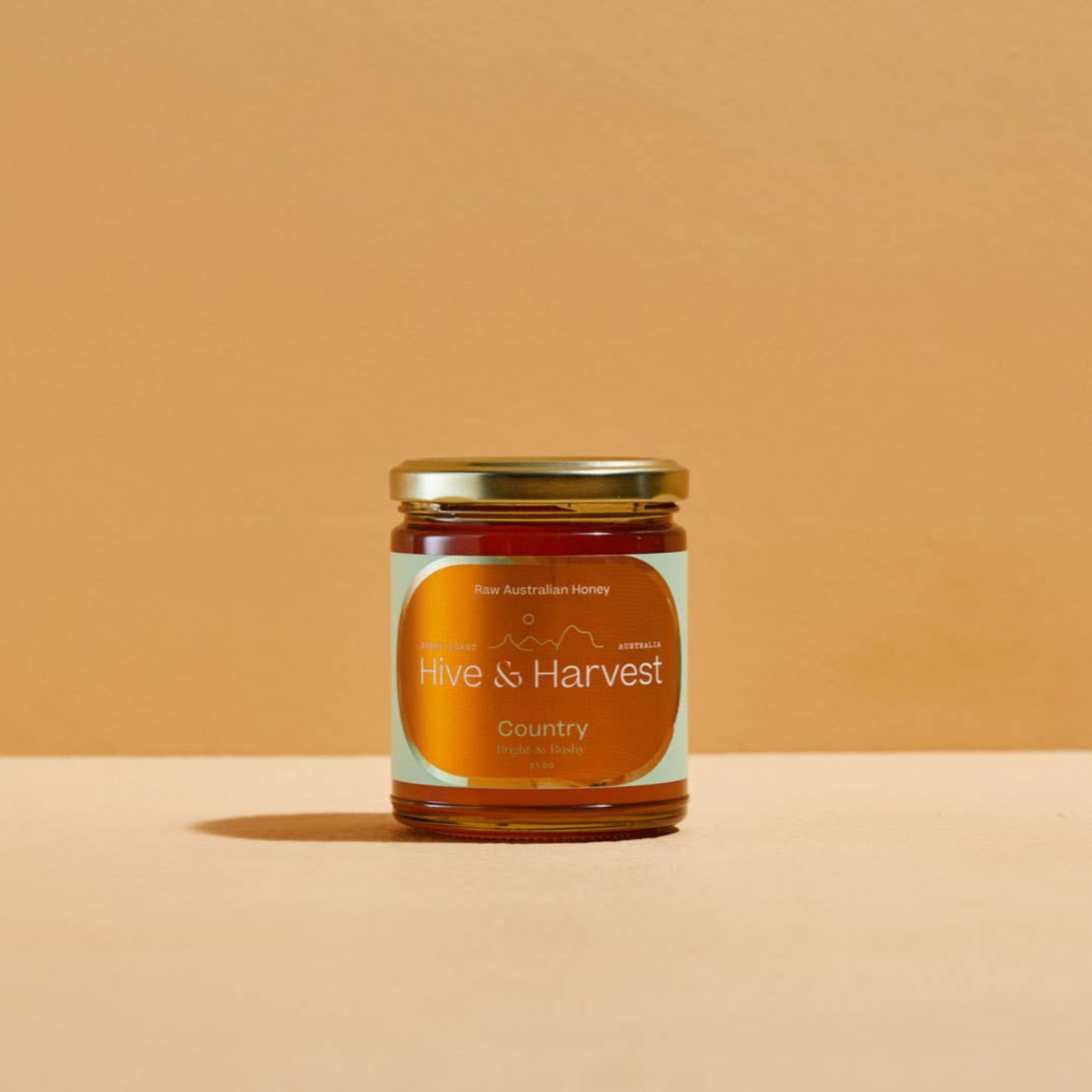 Jar of honey from 'Hive & Harvest' on a beige background