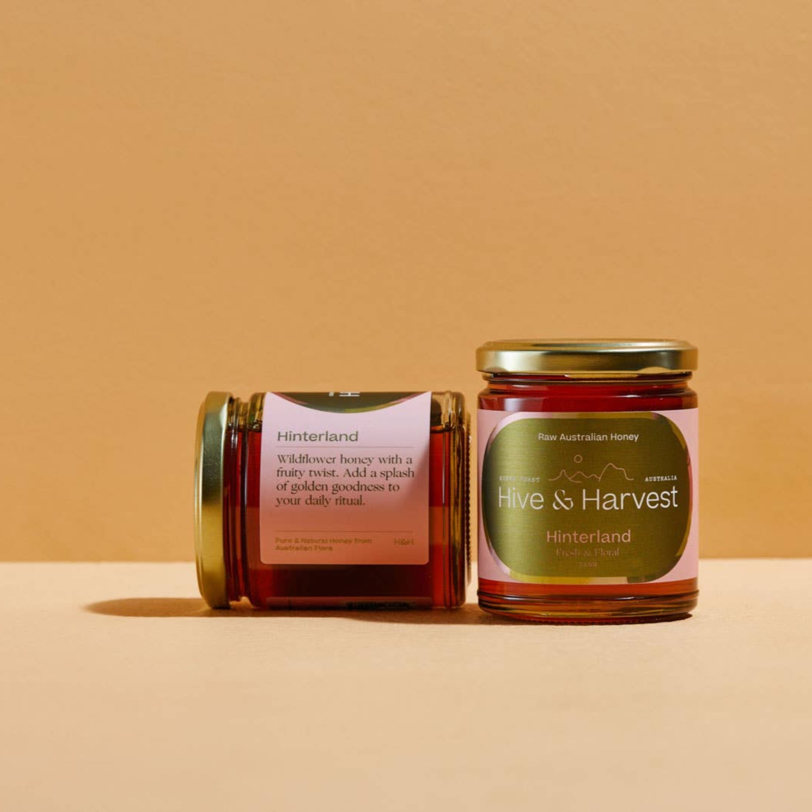 Jar of honey labeled 'Hive & Harvest' on a beige background