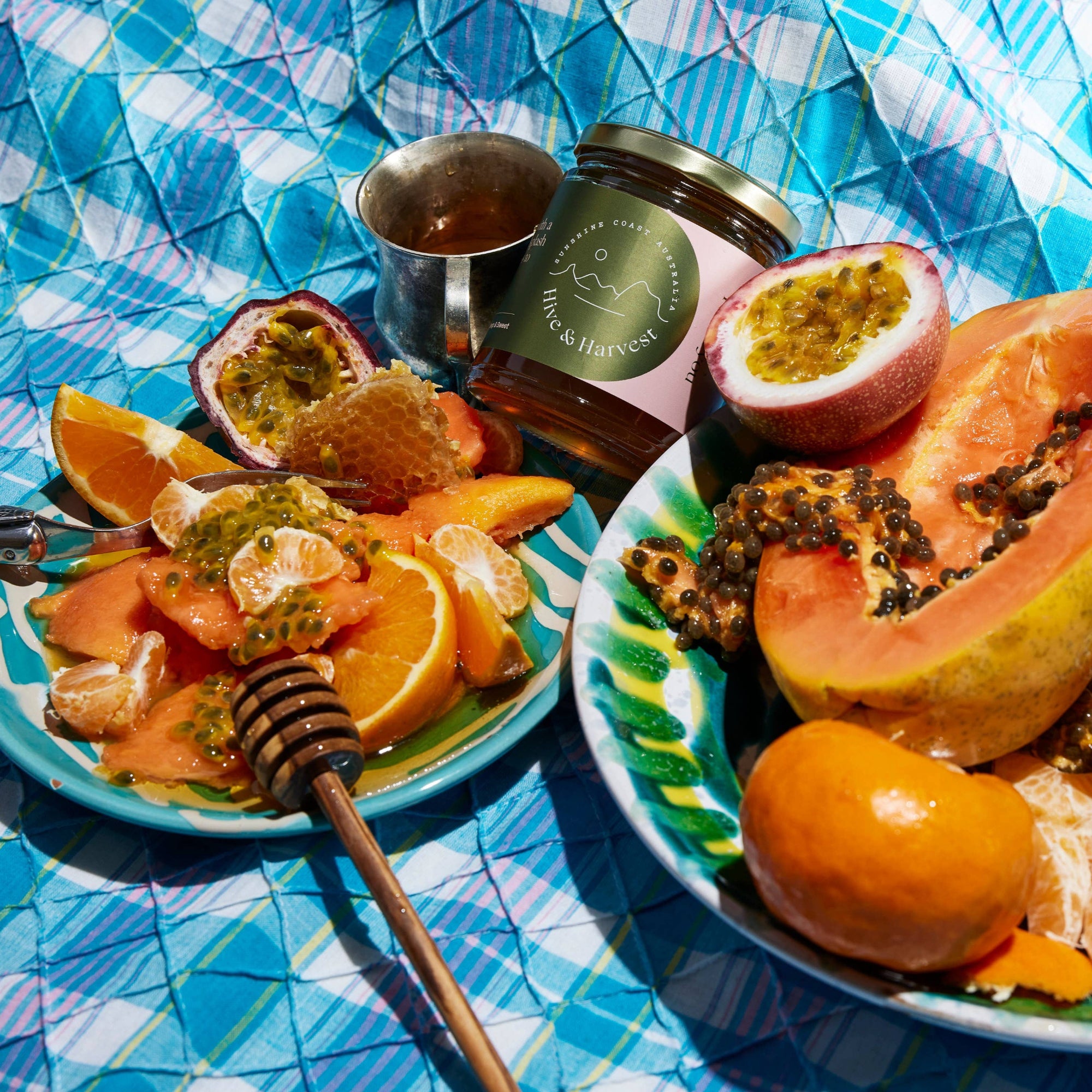Fruit platter with papaya, oranges, and passion fruits on a blue checkered tablecloth.