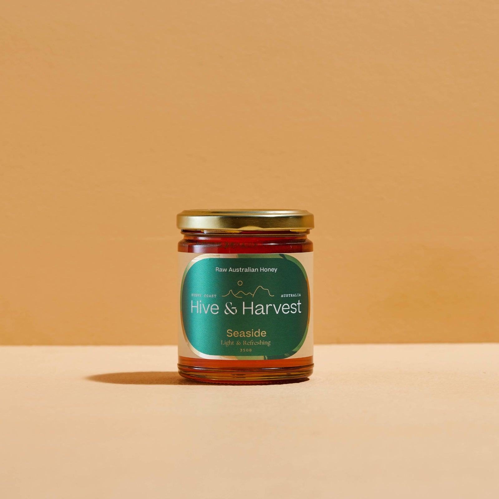 Two jars of honey from 'Hive & Harvest' on a beige background