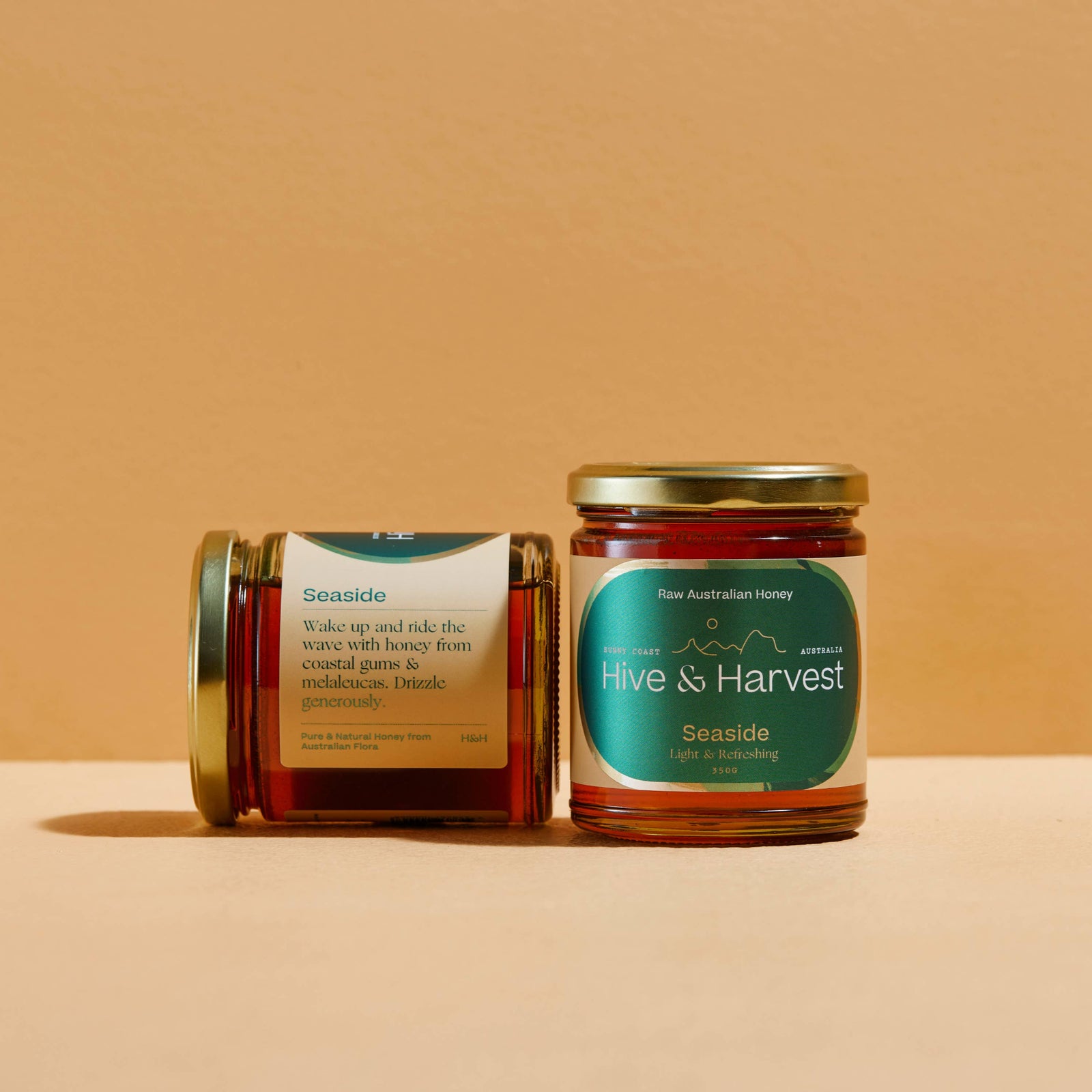 Two jars of honey from 'Hive & Harvest' on a beige background