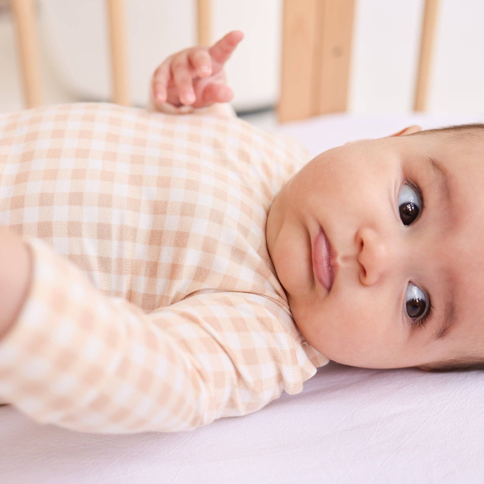 Baby wearing a pink checkered onesie on a white background
