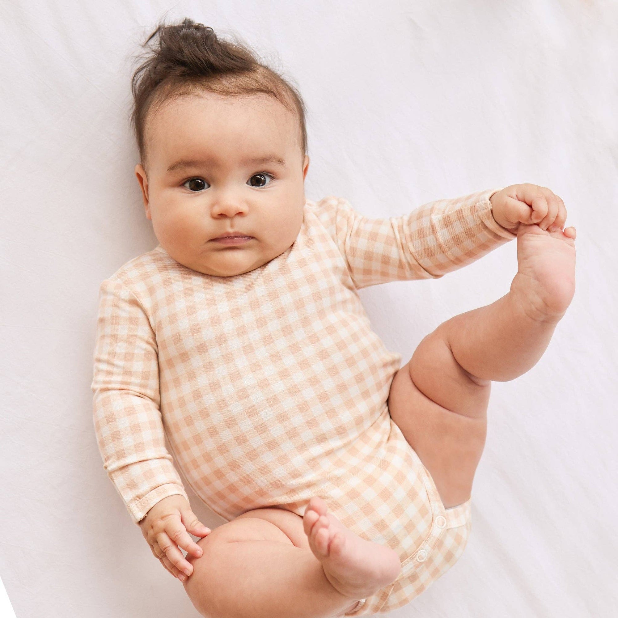 Baby wearing a pink checkered onesie on a white background