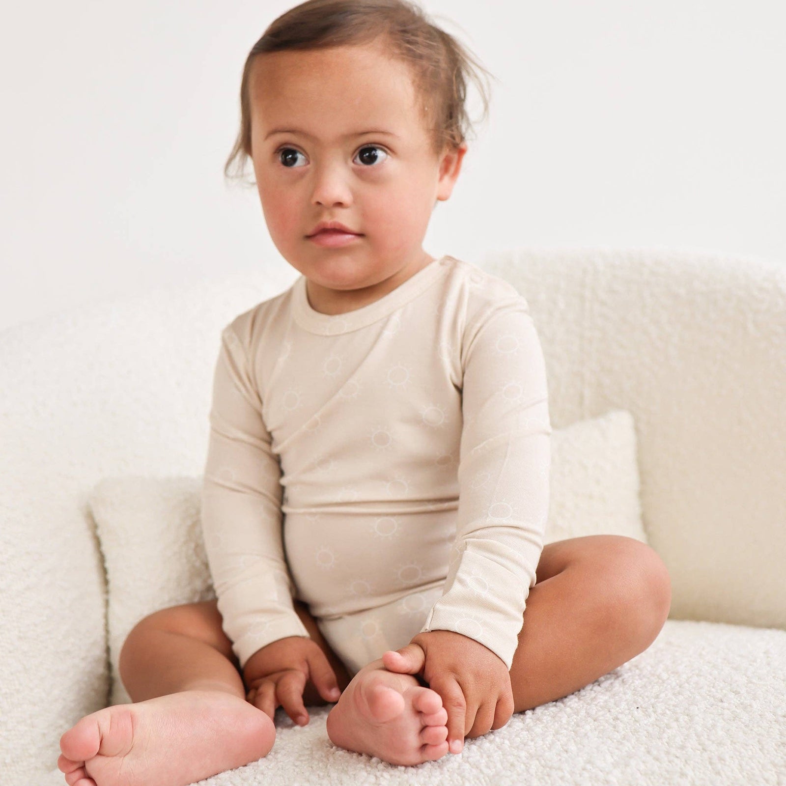 Beige baby bodysuit with long sleeves on a white background