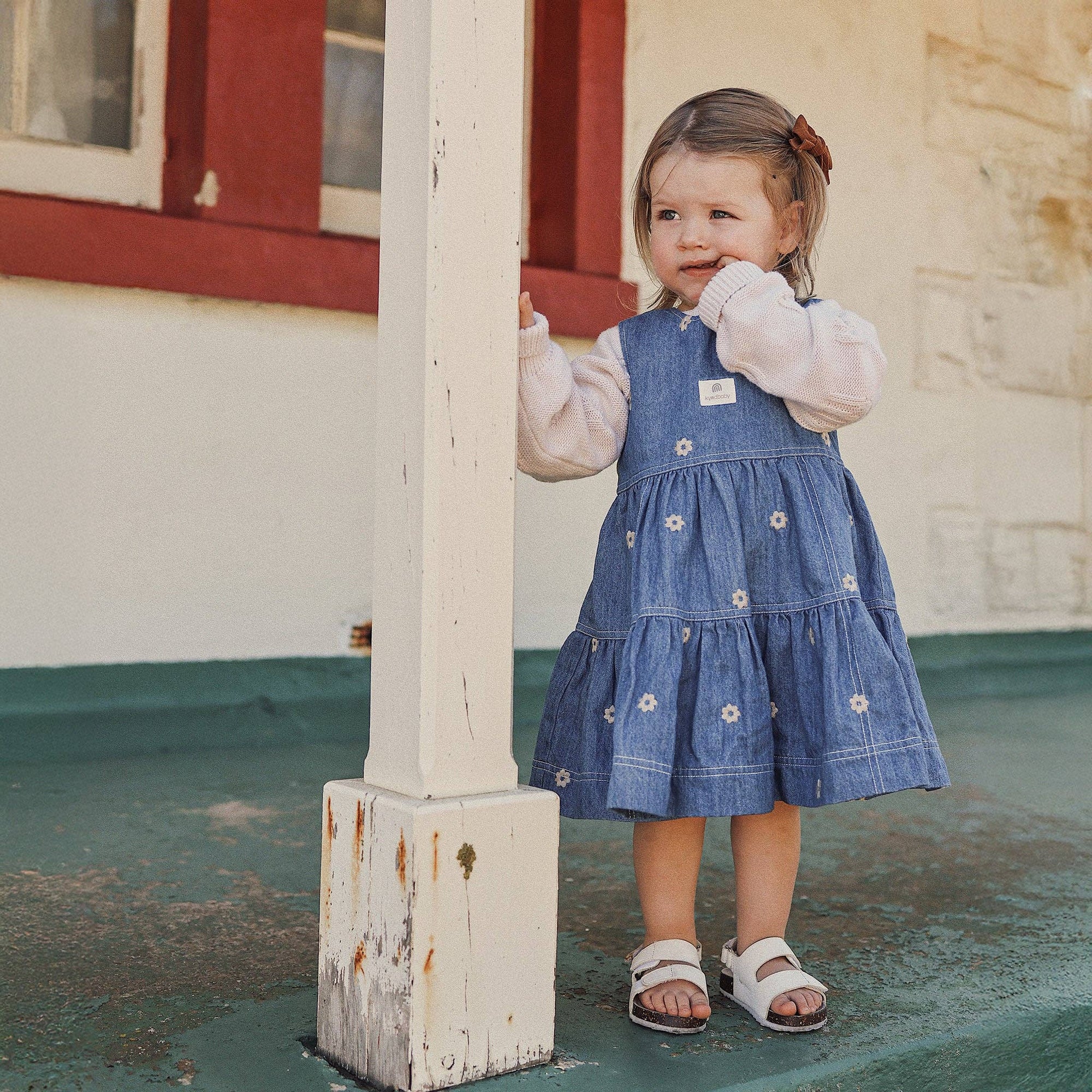 Young girl in a blue dress standing on a porch