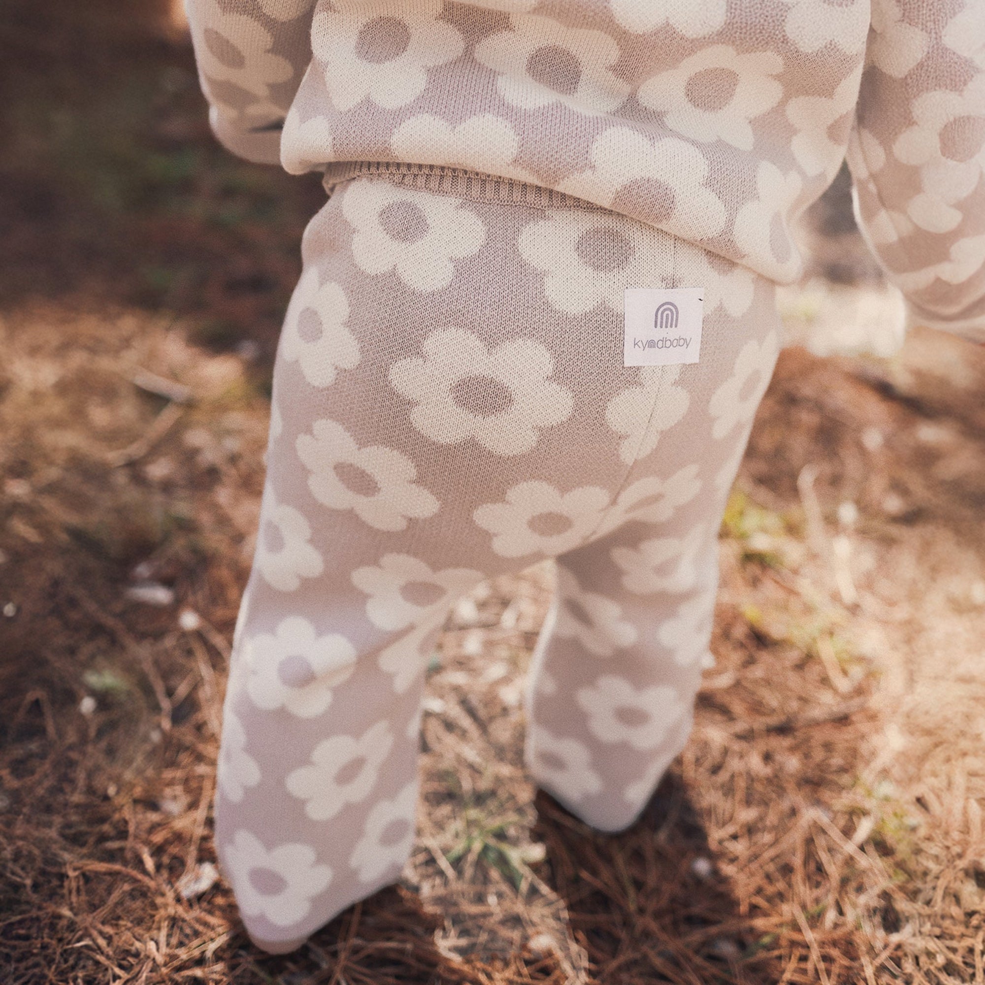 Children&#39;s floral-patterned pants with a visible brand tag on a natural background
