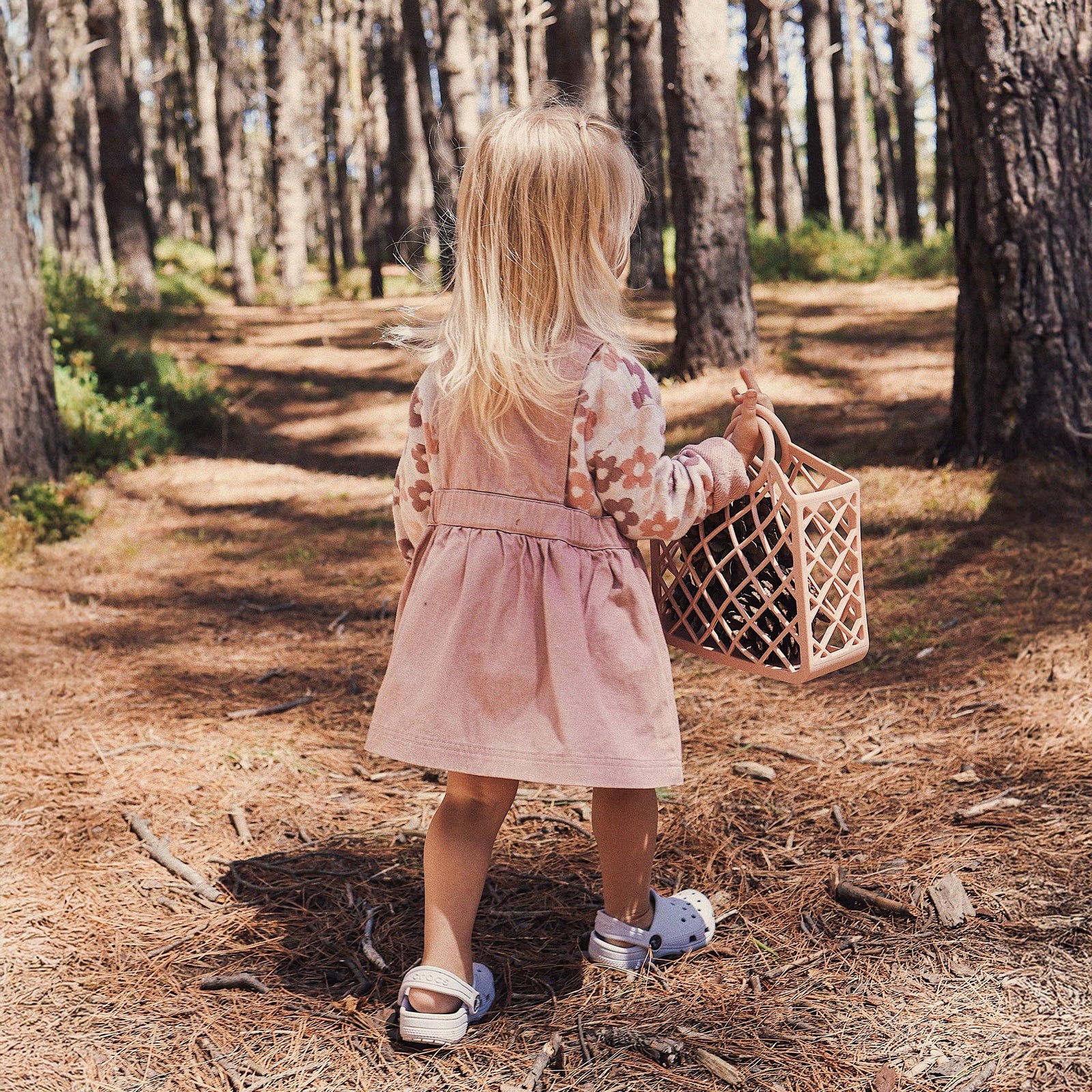 Child in a pink dress standing in a forest