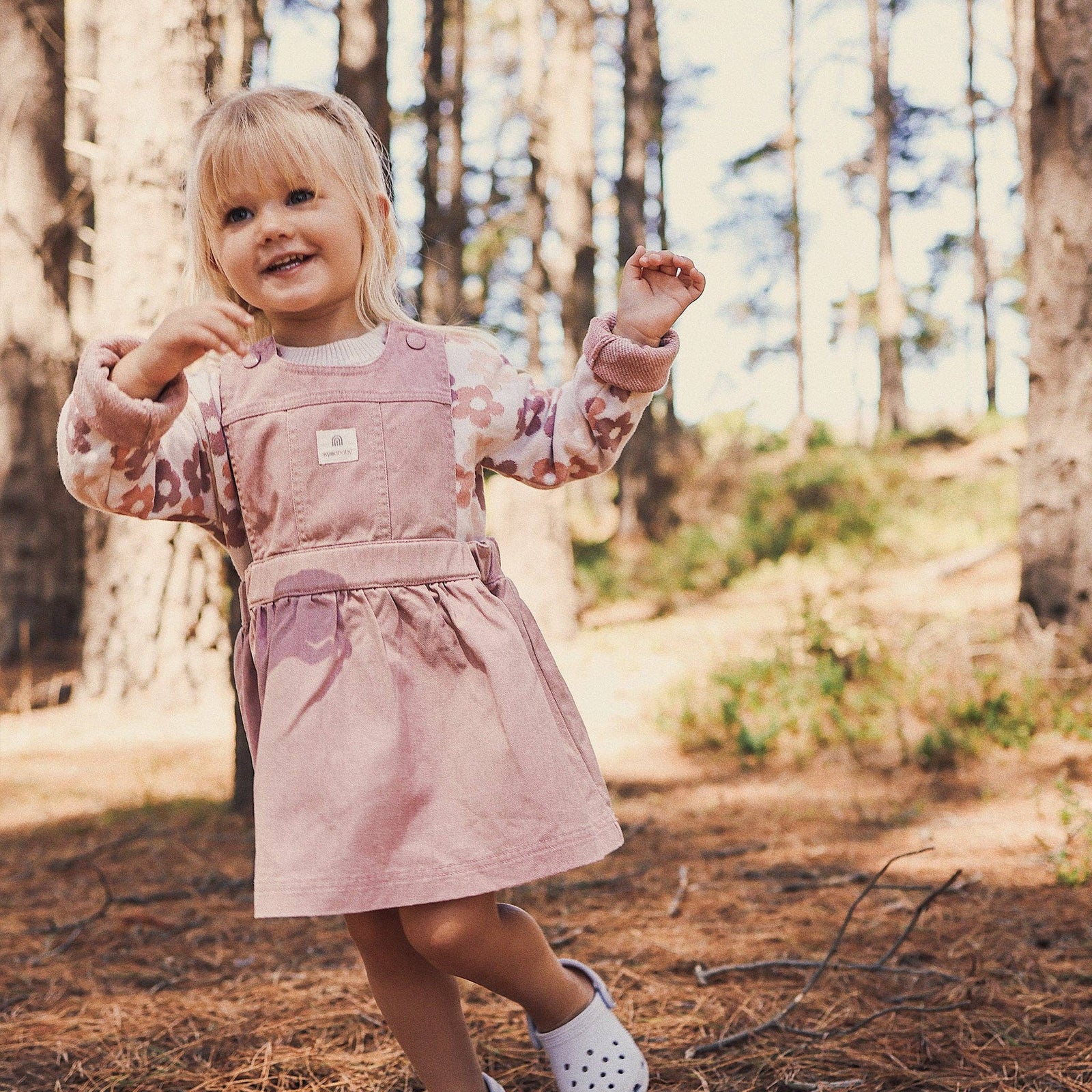 Child in a pink dress standing in a forest