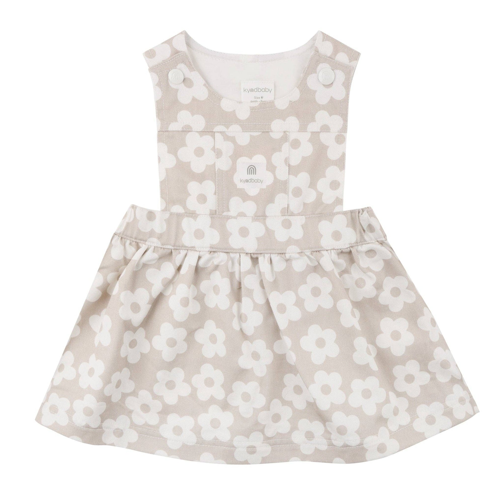 Children&#39;s dress with white floral pattern on a beige background