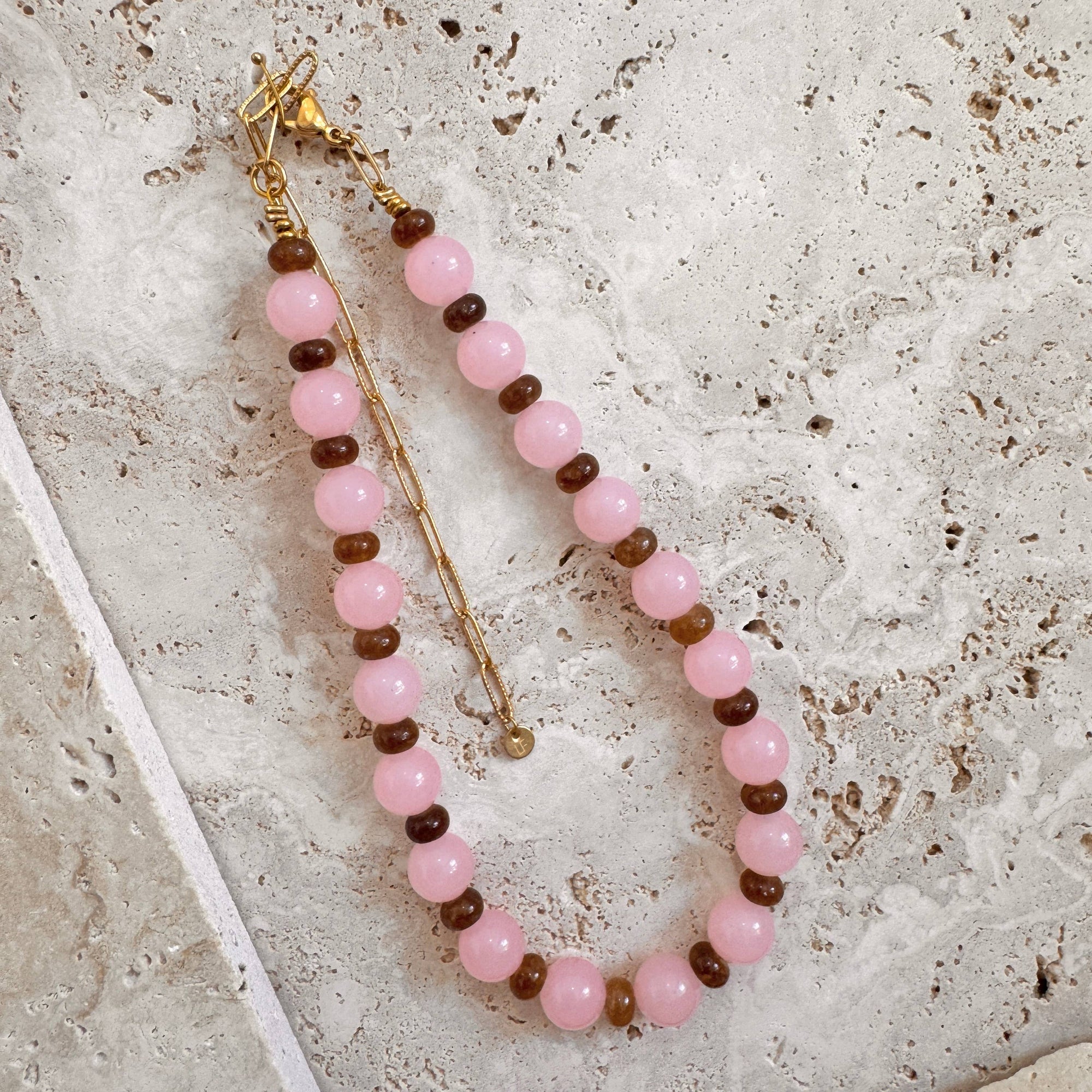 Beaded necklace with pink and brown beads on a textured surface