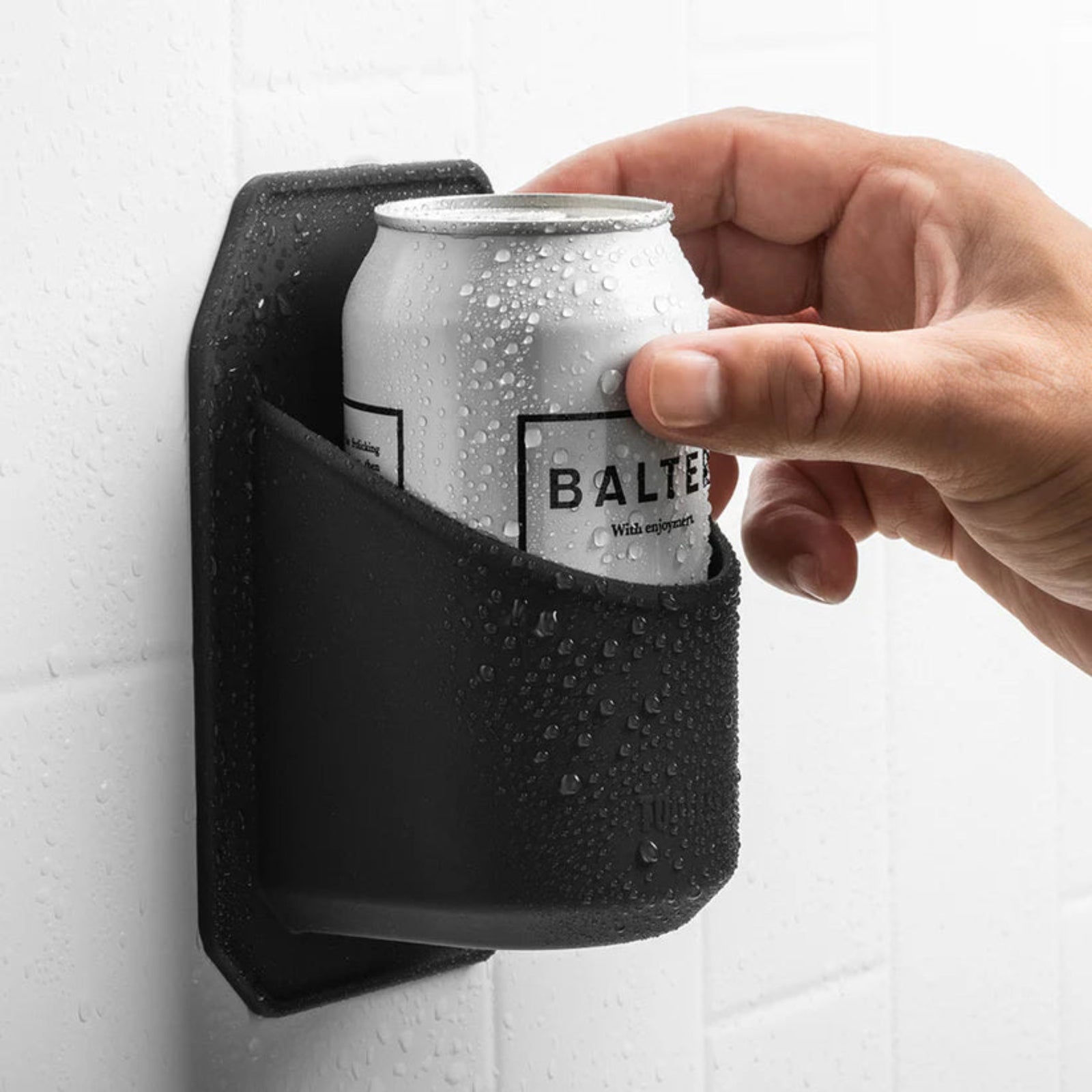 Hand placing a can into a black wall-mounted drink holder.
