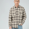 Man wearing a plaid shirt, light blue jeans, and brown shoes on a white background