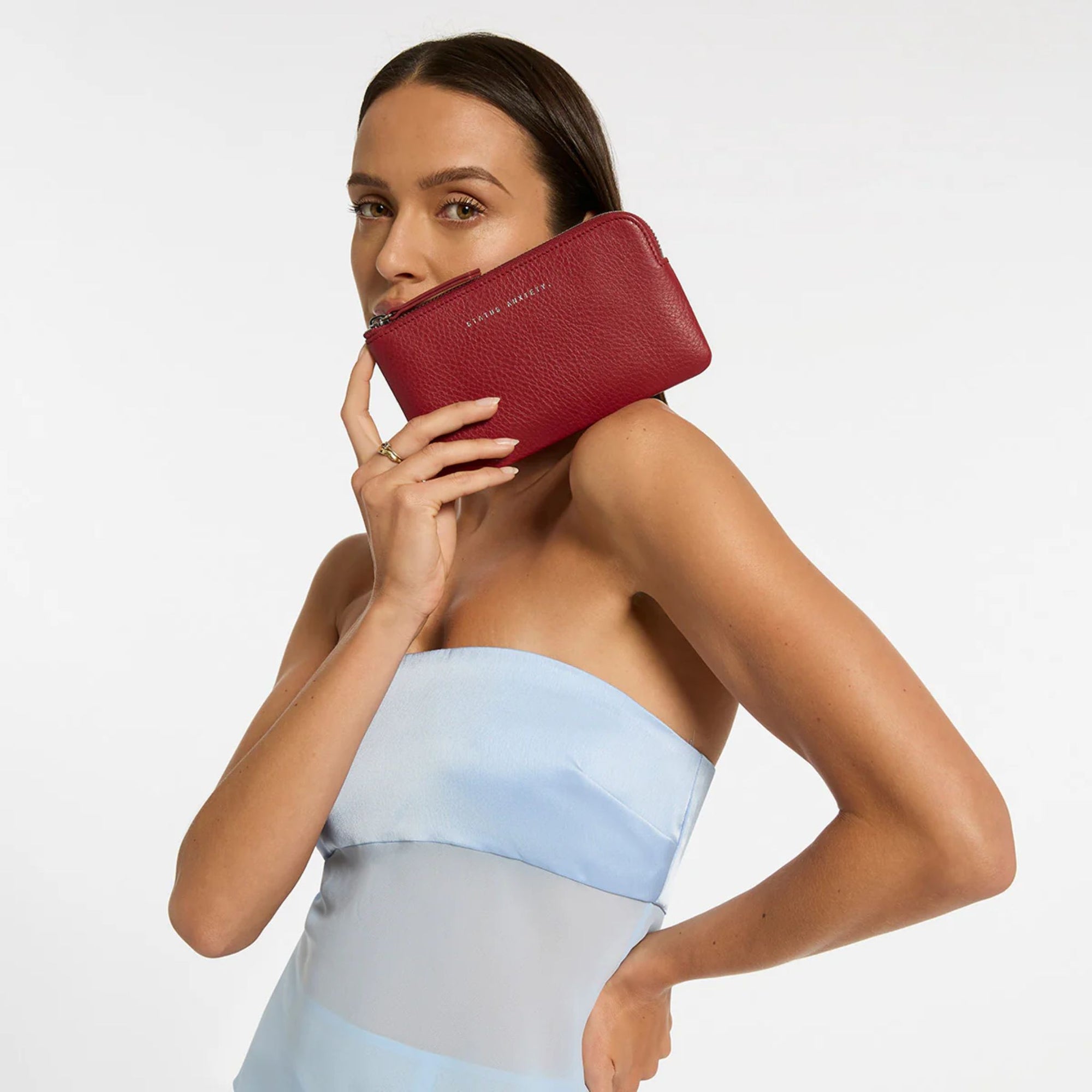 Red wallet with 'Status Anxiety' branding on a light gray background