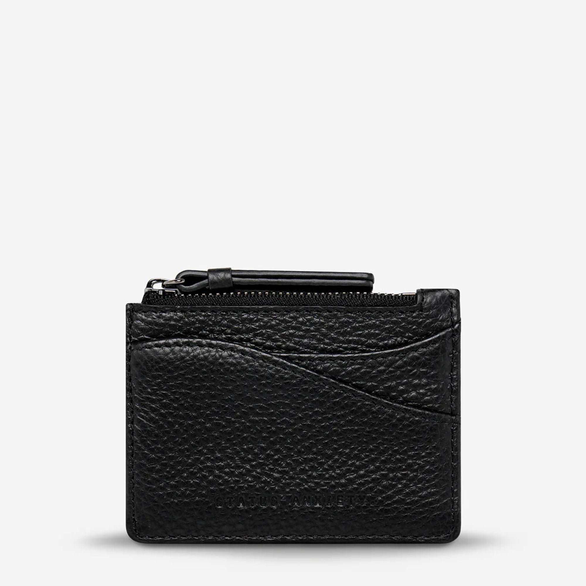 Woman holding multiple leather wallets of different colors against a neutral background