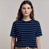 Woman wearing a navy striped t-shirt and beige pants against a neutral background
