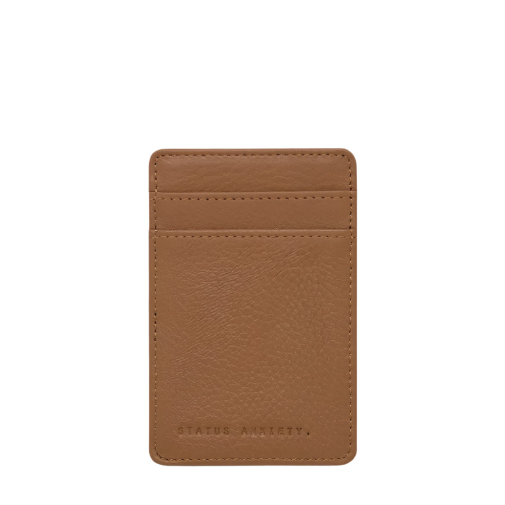 A brown leather wallet with multiple card slots and the brand 'STATUS ANXIETY' embossed on the front.