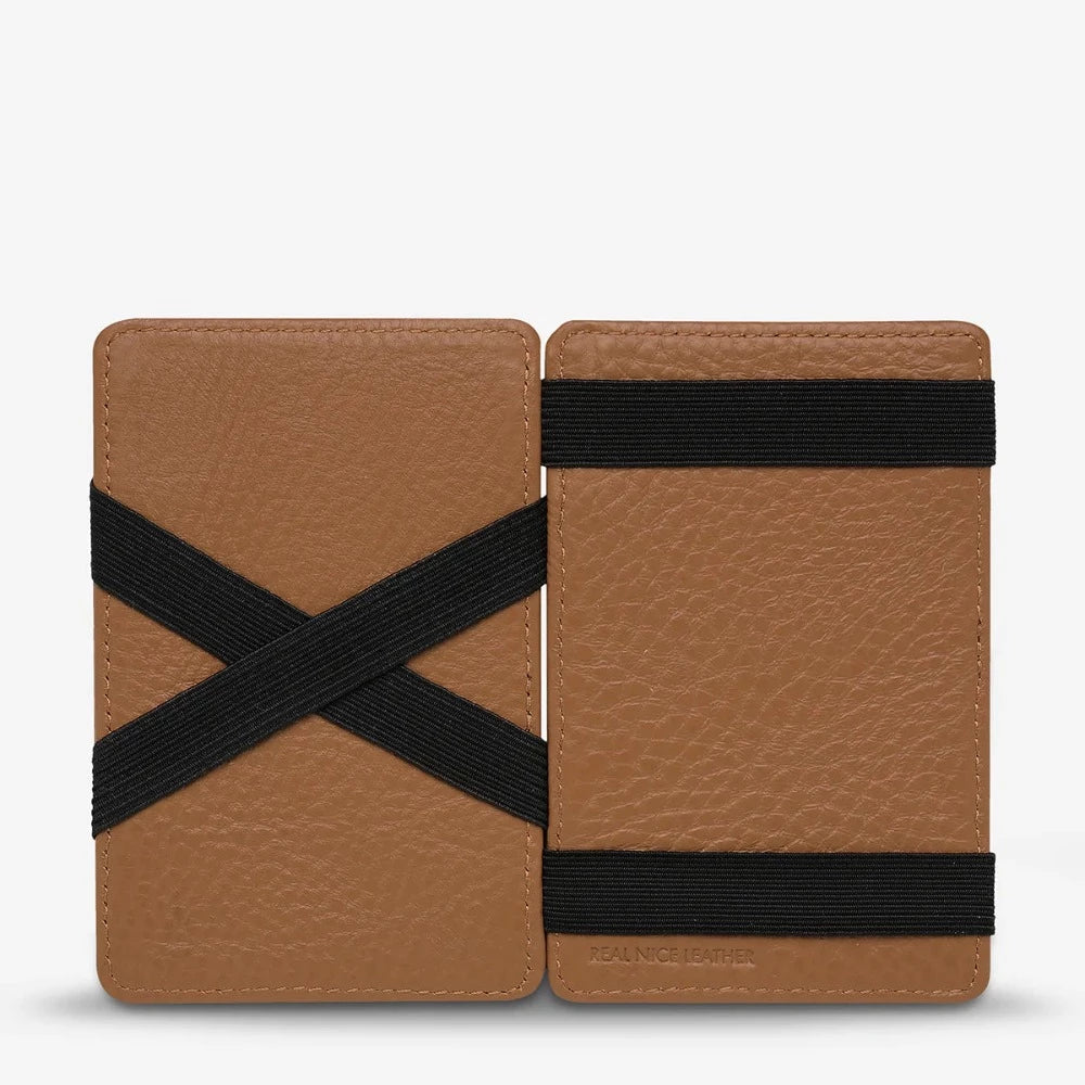 A brown leather wallet with multiple card slots and the brand 'STATUS ANXIETY' embossed on the front.